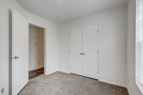 An empty room with two closets and a door.