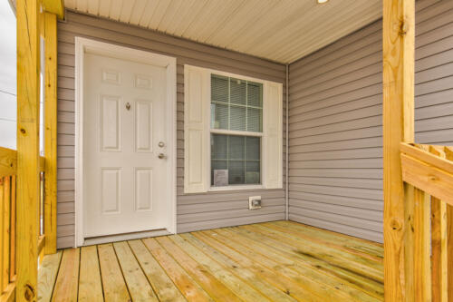 The front porch of a home with a white door and gray siding.