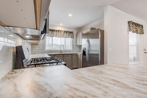 A kitchen with marble counter tops and stainless steel appliances.