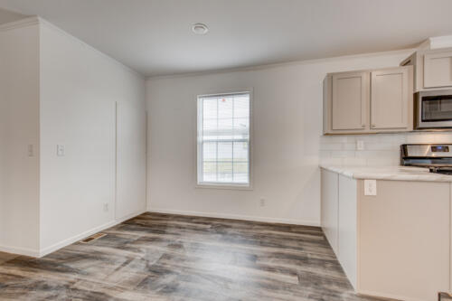 An empty kitchen with wood floors and a microwave.