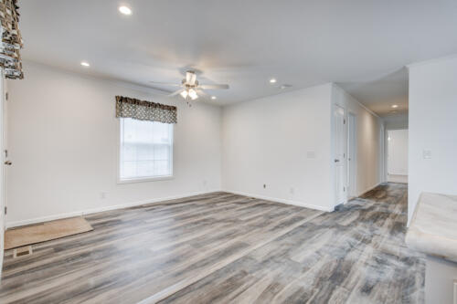 Empty living room with hardwood floors and ceiling fan.